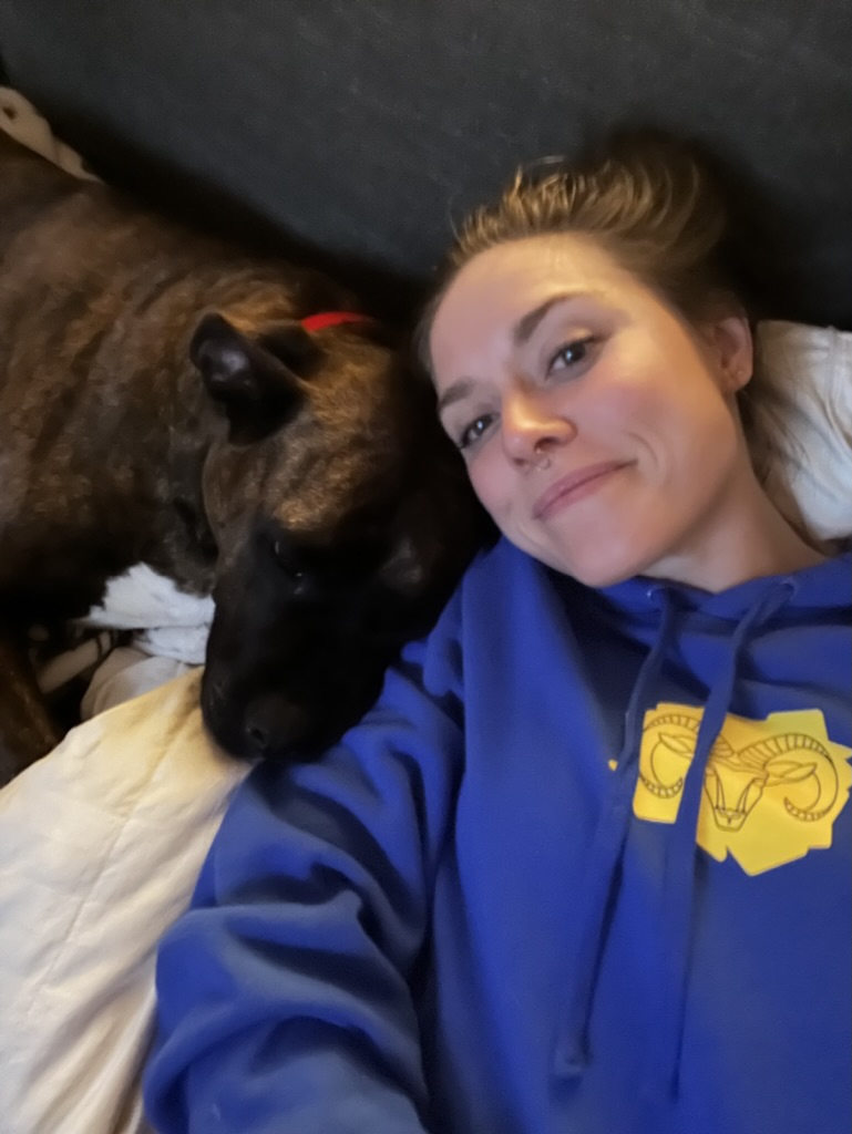Bree cuddling a brindle dog face-to-face on the couch