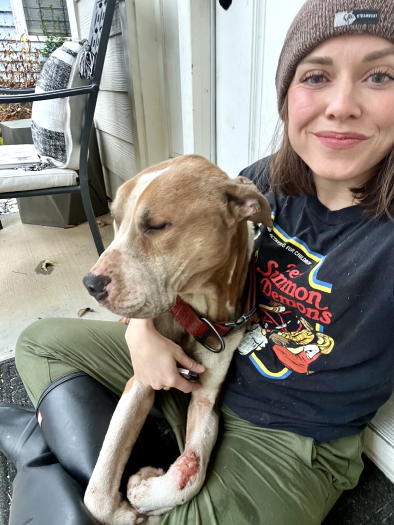 Bree on the porch with a brown pit-mix curled into her shoulder